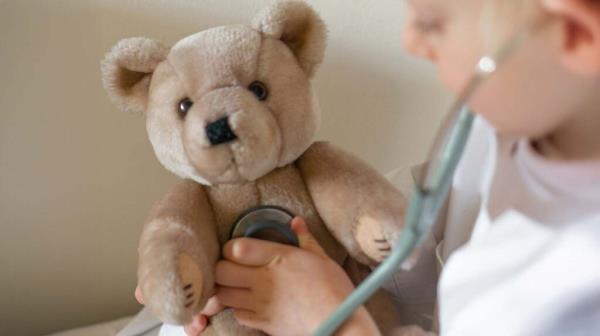 Child holding brown bear plush toy during a doctor visit. Image credit: Derek Finch, Unsplash.com